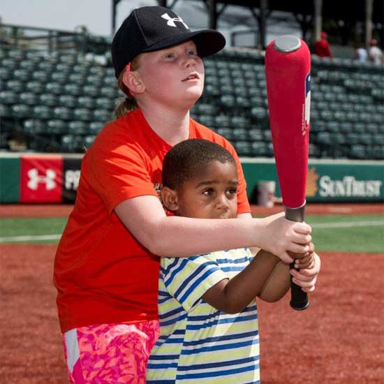 a kid helping another kid at bat